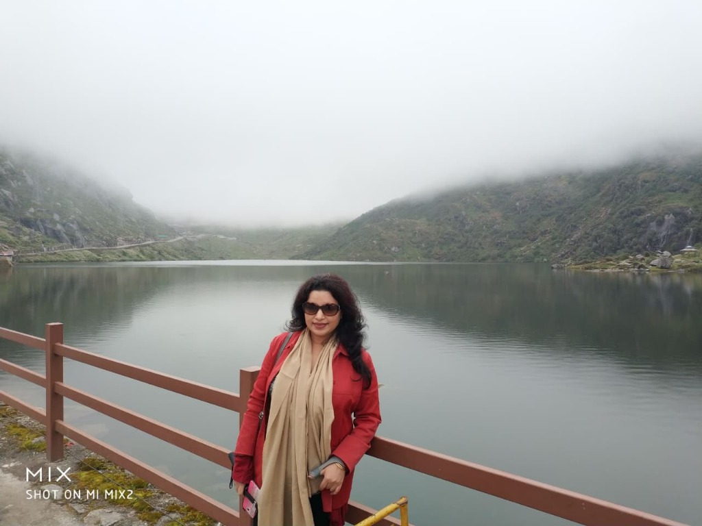 Traveler standing beside high-altitude Tsomgo Lake with misty mountain backdrop