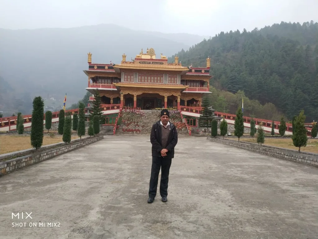 Paved monastery courtyard against the misty Dirang valley pine forest backdrop