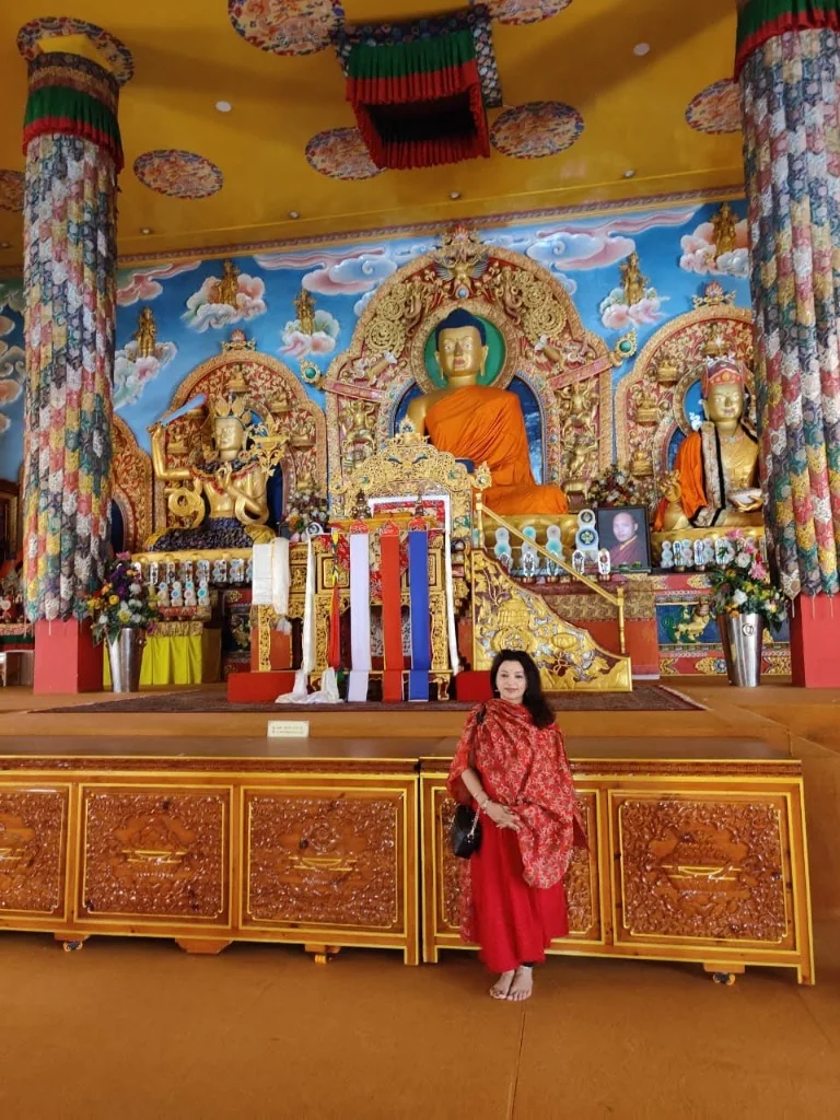 Traveler standing in front of the grand Shakyamuni Buddha statue at Palpung Sherabling Monastery