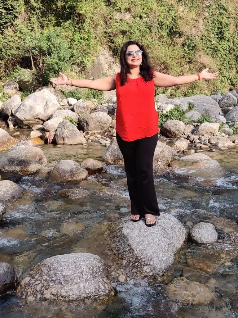 Traveler standing on a river rock in the middle of a flowing mountain stream in Palampur