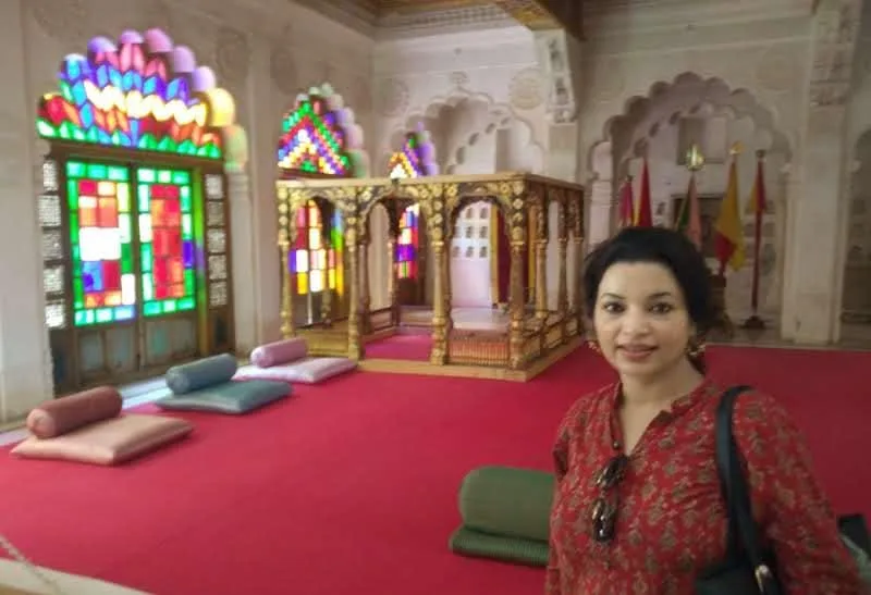 Colorful stained-glass windows and red-carpeted palace hall in Jodhpur