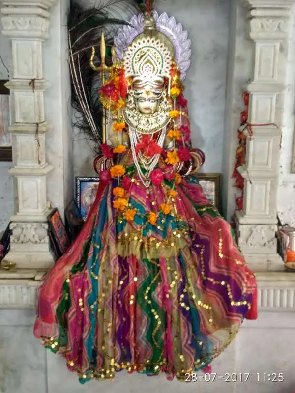Sacred idol of Goddess Ambamata adorned in vibrant silk attire, gold ornaments, and marigold garlands inside the sanctum sanctorum