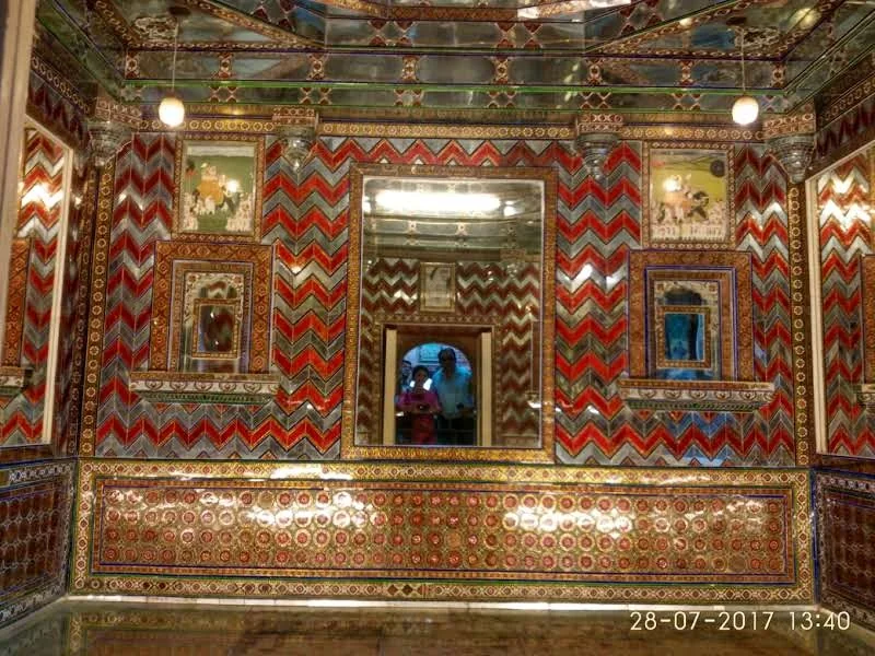 Ornate Kanch ki Burj glass mosaic chamber with red and silver chevron mirror patterns and royal miniature portraits